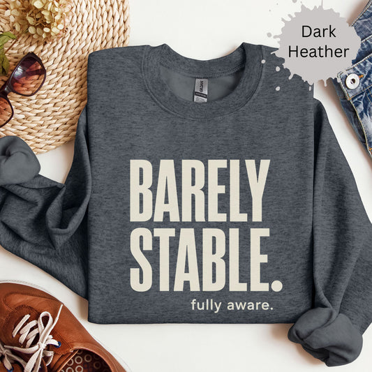 Womens sweatshirt with bold text reading “Barely Stable. Fully Aware.”