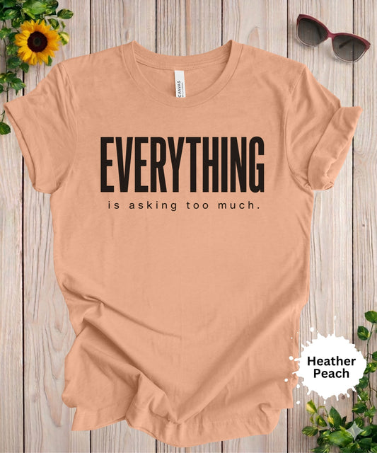 
women’s graphic T-shirt with the phrase “everything is asking too much” in bold typography