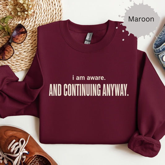 Womens sweatshirt with text reading “I am aware. And continuing anyway.”