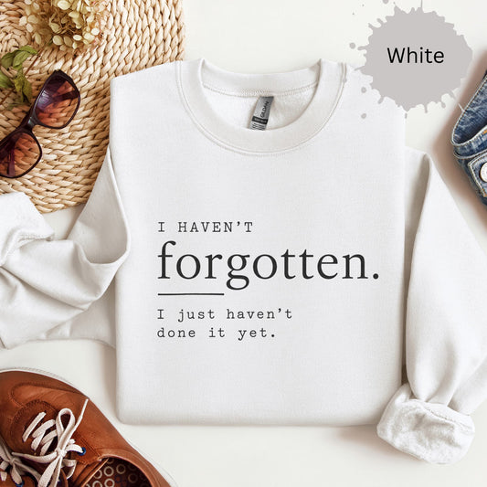 Ccrewneck sweatshirt with minimalist text reading “I haven’t forgotten. I just haven’t done it yet.”