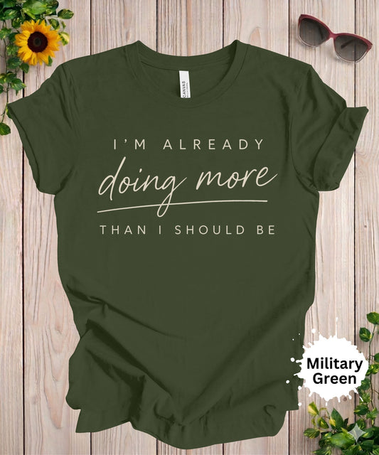Women’s graphic T-shirt with the phrase “I’m already doing more than I should be” in script and modern typography.