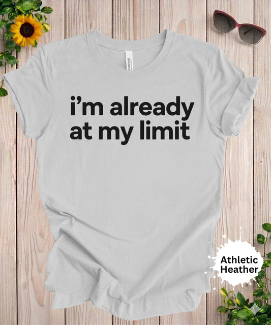 Light gray women’s graphic T-shirt with the phrase “i’m already at my limit” in bold black typography