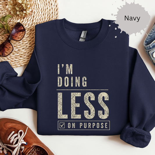 Crewneck sweatshirt with distressed bold text reading “I’m doing less on purpose.”