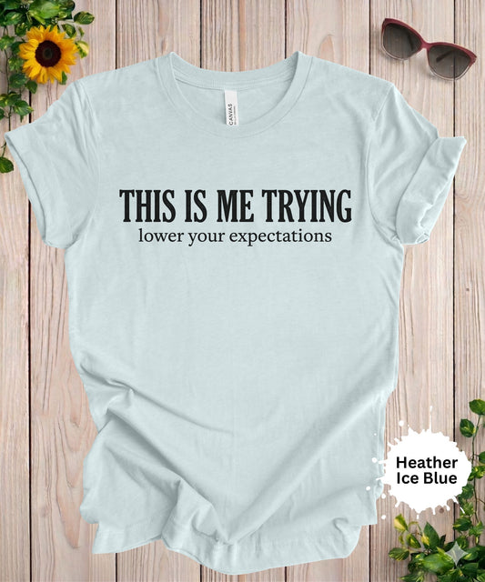Graphic T-shirt with text “This is me trying, lower your expectations” in minimalist black typography