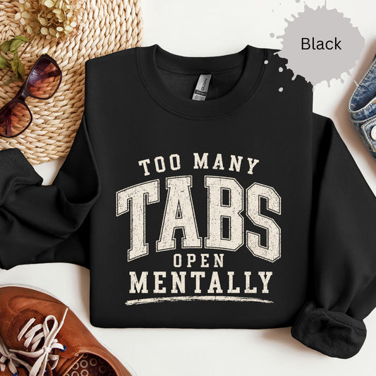 Crewneck sweatshirt with distressed varsity text reading “Too many tabs open mentally.”