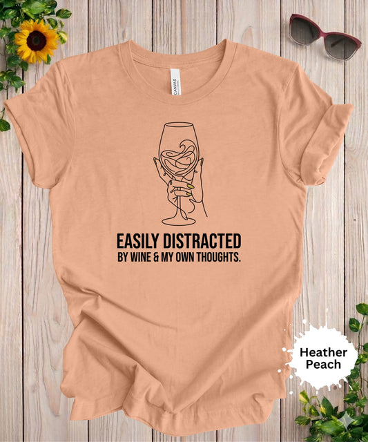 Woman wearing easily distracted by wine graphic t-shirt with minimalist wine glass illustration and humorous phrase