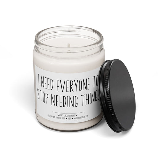 I Need Everyone to Stop Needing Things scented soy candle in a clear glass jar with humorous typography label.