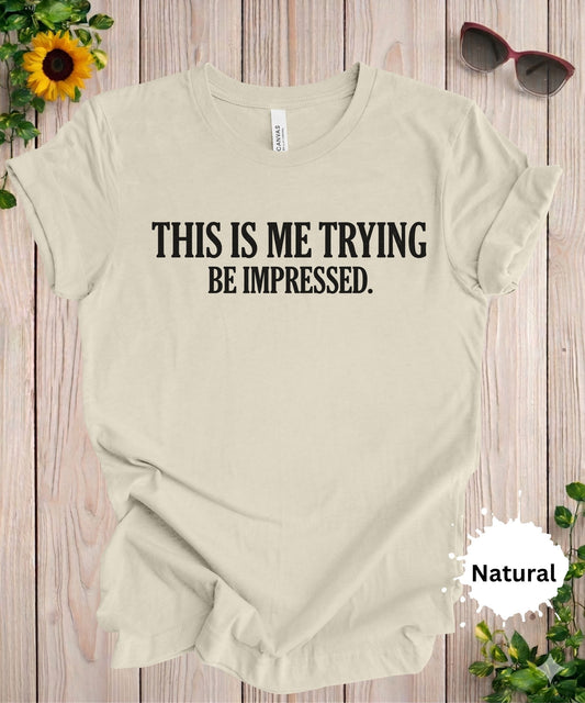 Graphic T-shirt with text “This is me trying, be impressed” on a green background in bold typography